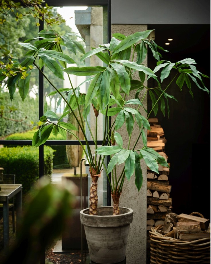 Großer künstlicher Baum in einem lichtdurchfluteten Innenraum mit Glasfront